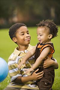 Big brother and little brother playing with ball in park