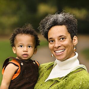 Head and shoulder portrait of woman holding boy and smiling
