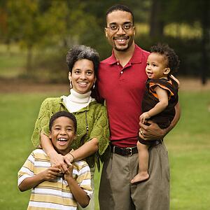 Portrait of happy smiling family of four in park.