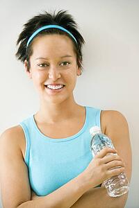 Woman in exercise clothes holding bottle of water smiling