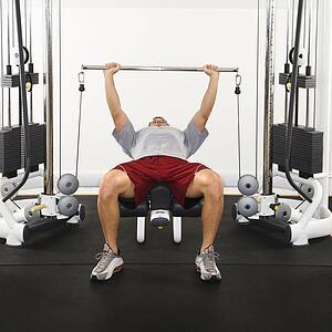 Man at gym lifting weights on weight machine.