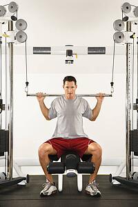 Man at gym lifting weights on weight machine