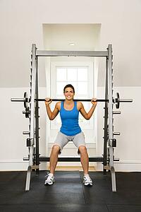 Woman lifting weights in gym smiling.