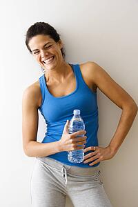 Woman in fitness attire holding bottle and laughing