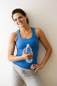 Portrait of woman in fitness attire holding water bottle and smiling