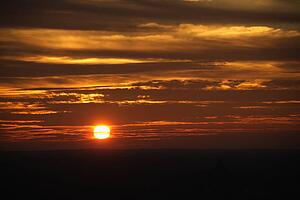 Sun setting in orange sky with clouds