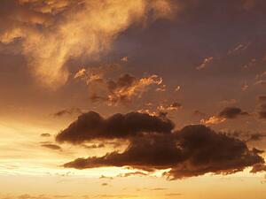 Fluffy clouds in orange-colored sky at sunset