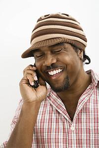 Man wearing hat and smiling while talking on cell phone