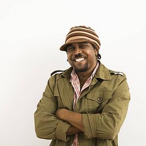 Mid-adult man wearing hat and smiling at viewer with arms crossed