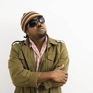 African-American mid-adult man wearing hat and sunglasses with arms crossed looking up.
