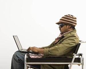 Man wearing hat and typing on laptop computer