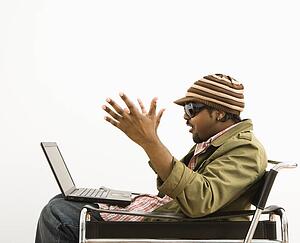 Man wearing hat and making surprised expression at laptop computer
