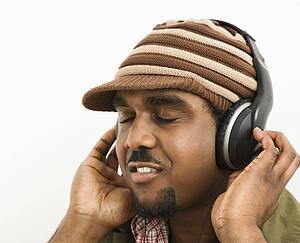 Man wearing knit hat and listening to headphones with eyes closed