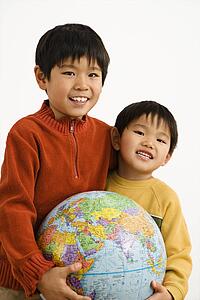 Boys holding world globe and smiling.