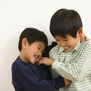 Two young Asian brothers playing and laughing.
