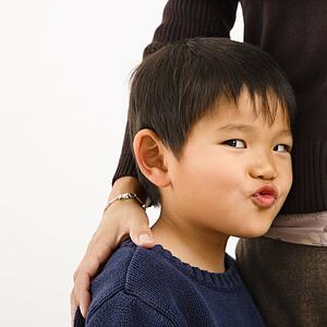 Boy making funny face standing next to mother