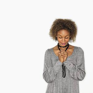 Woman with hands clasped together in prayer and eyes closed