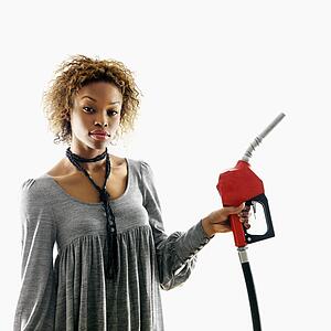 Portrait of pretty young woman holding gas pump nozzle on white background