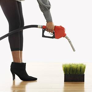 Woman holding gasoline pump nozzle over green grass