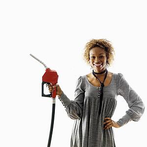 Woman holding gasoline pump nozzle smiling