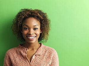 Portrait of smiling young woman on green background.