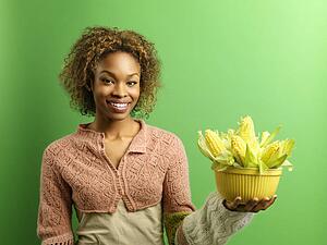 Woman standing holding bowl full of ears of corn