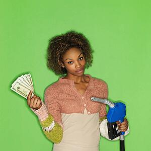 Portrait of pretty young woman standing against green background holding gasoline pump nozzle and money.
