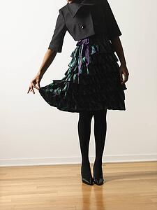 Woman wearing ruffled dress holding it out daintily with fingers