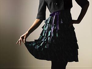Woman wearing ruffled dress holding it out gracefully with fingers