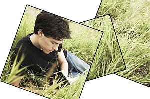 Teenage boy reading in the grass