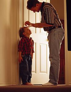 Father measuring son on door frame