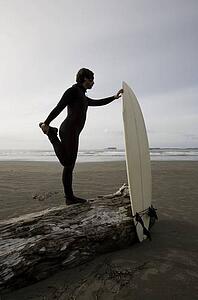 Surfer stretching on beach