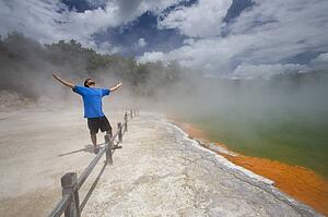 Man at Champagne Pool at geothermal site, Wai-O-Tapu Thermal Wonderland on North Island of New Zealand