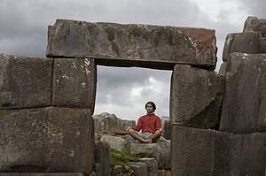 A young man meditates in ancient Incan ruins outside Cuzco, Peru