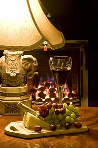 Cheese, grapes and glass of wine on table by lamp