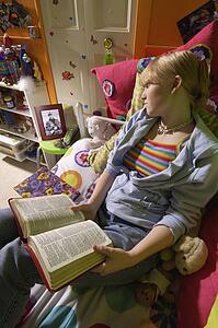 Girl reading Bible in bedroom