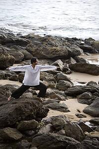 A man stretching on a rocky beach in Koh Lanta, Thailand