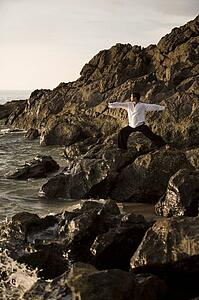 A man stretching on a rocky beach in Koh Lanta, Thailand