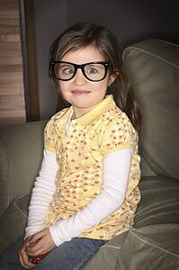 A girl wearing glasses, crossing her eyes