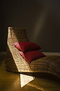 Wicker lounging chair with red pillows