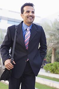 Businessman walking outdoors smiling (high key/selective focus)