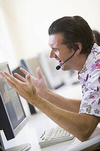 Man in computer room wearing headset looking frustrated