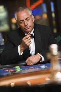 Man in casino playing roulette and looking at chip (selective focus)