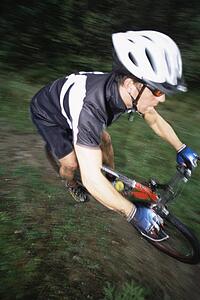 Man outdoors on trails riding bicycle (selective focus)