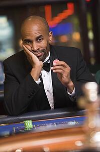 Man in casino playing roulette and holding chip (selective focus)