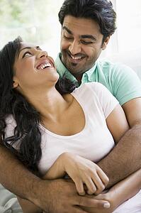 Couple in living room embracing and smiling (high key)