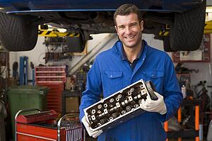 Mechanic holding car part smiling