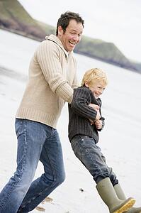 Father holding son at beach smiling