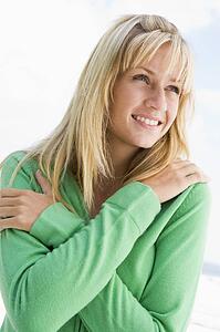 Blonde woman in a green sweater posing outdoors