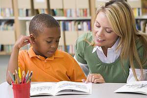 Student in class reading with teacher